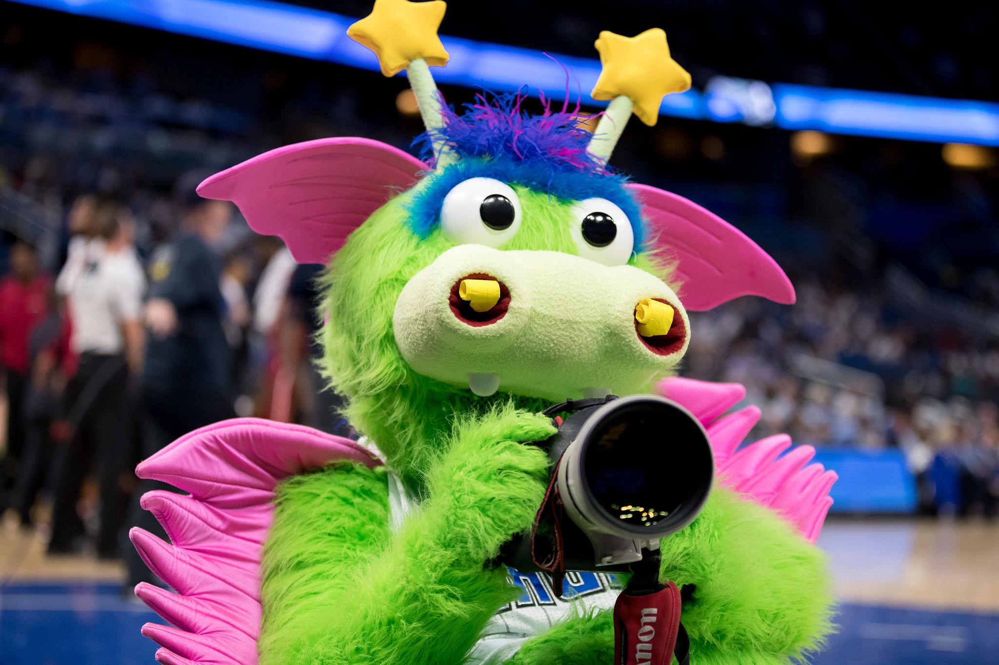 Stuff the Magic Dragon holding a camera at an Orlando Magic game
